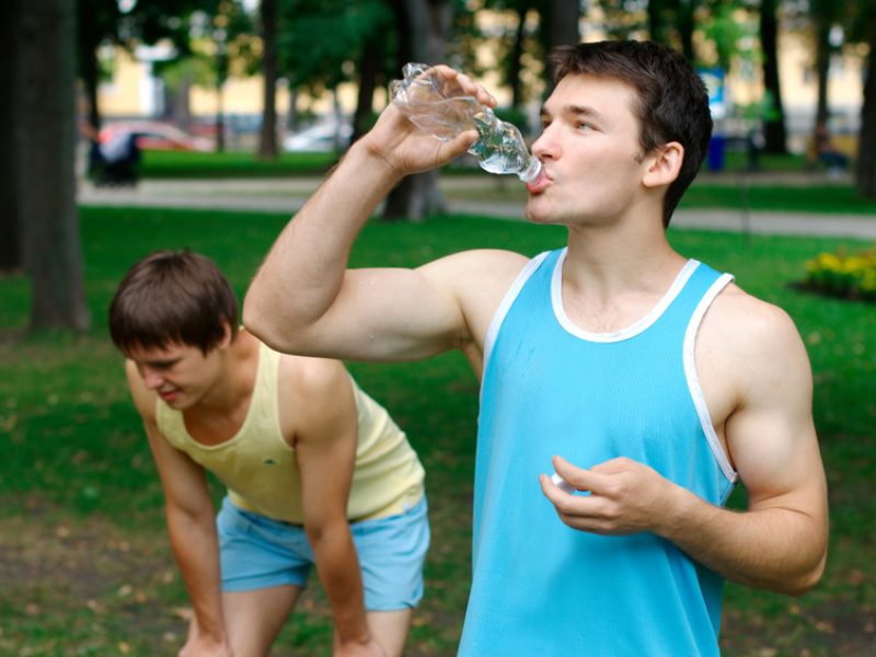 Young sportsman drinking water at the park